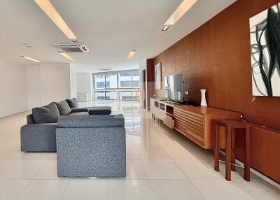 Spacious and modern living room with grey sectional sofa, wall-mounted TV, and contemporary decor.