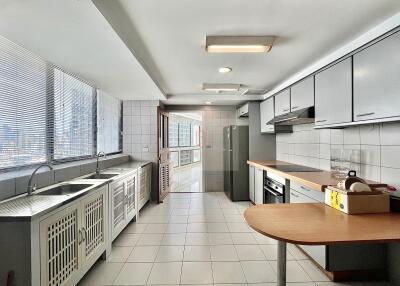 Modern, spacious kitchen with natural light from large windows and fully equipped with appliances and cabinetry