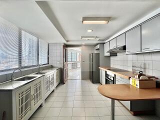 Modern, spacious kitchen with natural light from large windows and fully equipped with appliances and cabinetry