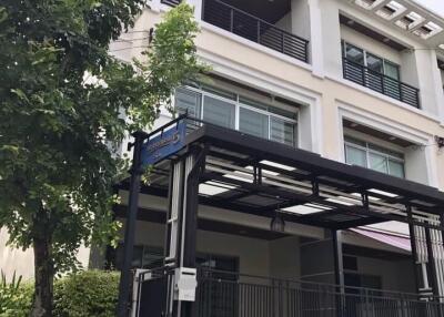 Exterior view of a modern multi-level building with a gated entrance and a tree