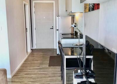 Modern living area with a seamless integration of a small dining and kitchen space, featuring wooden flooring and contemporary furnishings