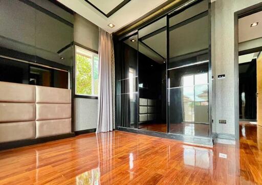 Contemporary bedroom with large mirrored closet doors and polished hardwood floors