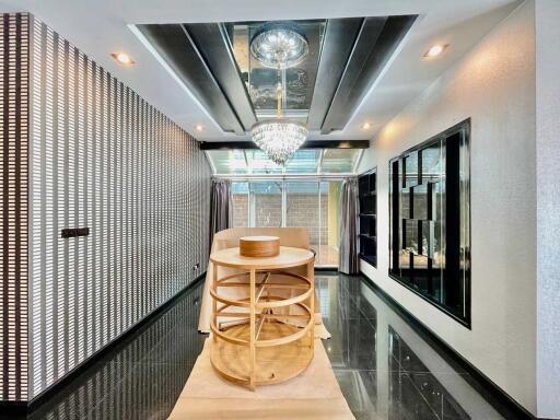 Modern hallway with chandelier and reflective ceiling