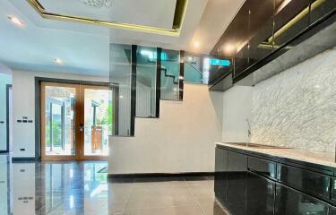 Modern kitchen area with sleek black cabinets and marble backsplash