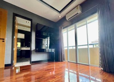 Modern bedroom with wooden flooring and glass door leading to balcony