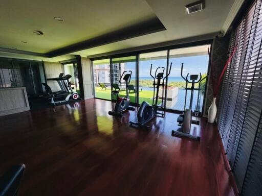 Well-equipped home gym with cardio machines and a view of the outdoor pool and surroundings