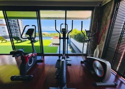 Modern fitness room with exercise equipment and large windows with a garden view