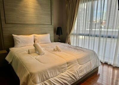 Modern bedroom with a large window and a neatly made bed with white linens and a headboard.