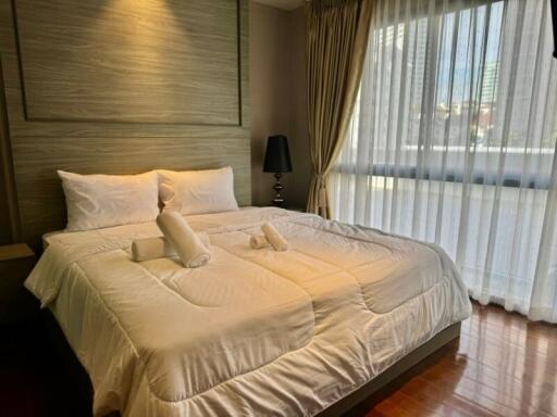 Modern bedroom with a large window and a neatly made bed with white linens and a headboard.