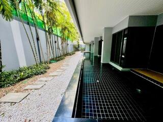 Outdoor corridor with black tiled walkway and garden area