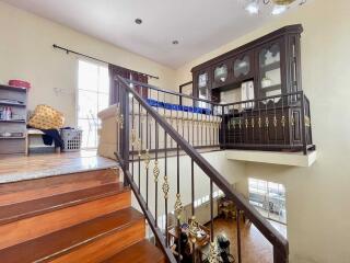 A two-level interior view with wooden staircase, railings, and furniture