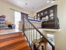 A two-level interior view with wooden staircase, railings, and furniture