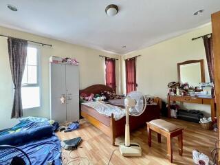 Bedroom with wooden floor, bed, wardrobe, and fan