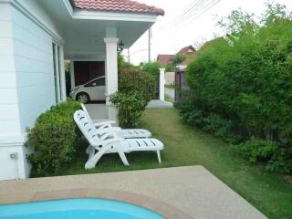 Outdoor area with lounge chairs, pool, greenery, and carport