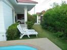 Outdoor area with lounge chairs, pool, greenery, and carport