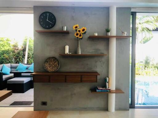 Modern living room with decorative shelves, sunflowers, and a view of the pool