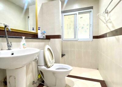 Bright and clean bathroom with toilet, sink, mirror, and window.