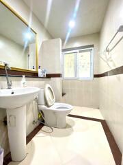 Bright and clean bathroom with toilet, sink, mirror, and window.