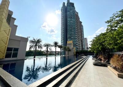 View of outdoor pool with surrounding buildings and lounge chairs