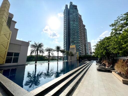 View of outdoor pool with surrounding buildings and lounge chairs