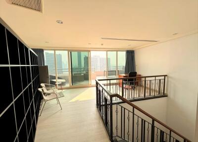 Spacious living room with a loft area, large windows, and city view