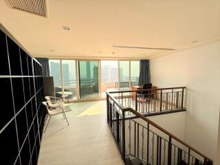 Spacious living room with a loft area, large windows, and city view