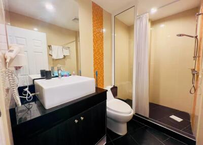 Modern bathroom with black countertop, sink, toilet, and walk-in shower