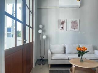 Modern living room with white sofa, wall art, and tulip centerpiece