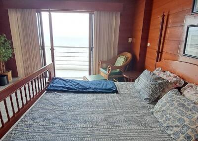 Bedroom with large bed, wooden walls, and balcony view