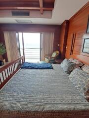 Bedroom with large bed, wooden walls, and balcony view