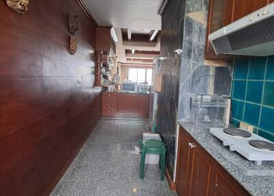 A well-lit, narrow kitchen with wooden cabinetry and marble countertops