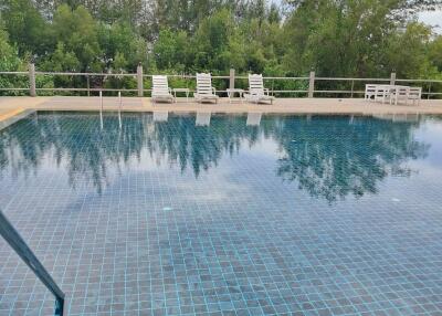 Outdoor swimming pool with lounge chairs and wooded backdrop