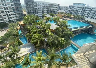 Aerial view of a modern apartment complex with multiple swimming pools and lush greenery.