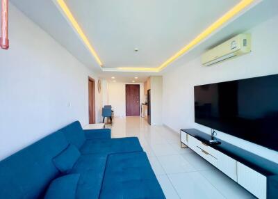 Modern living room with blue sofa, wall-mounted TV, and ambient lighting