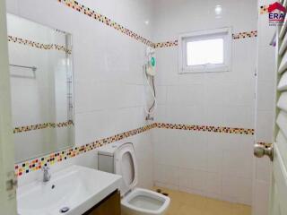 Bathroom with white tiles, sink, toilet, and electric water heater