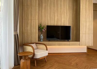Modern living room with wooden paneling, TV, armchair, and side table