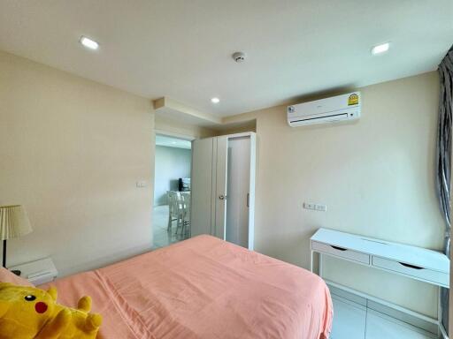 Bedroom with a pink bedspread, white wardrobe, and air conditioning unit