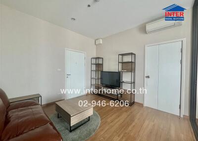 Minimalist living room with brown leather sofa, TV stand, and wooden floor