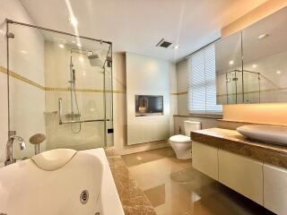 Modern bathroom with glass shower, bathtub, and large vanity mirror