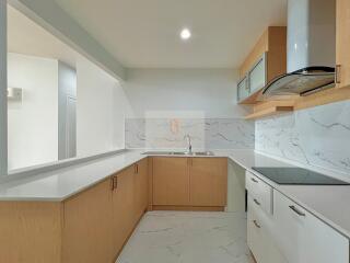 Modern kitchen with light wood cabinets and marble countertops