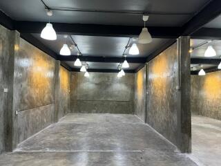 Empty industrial-style interior space with exposed concrete walls and multiple ceiling lights