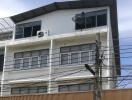 Exterior view of a multi-story building with satellite dish and AC unit