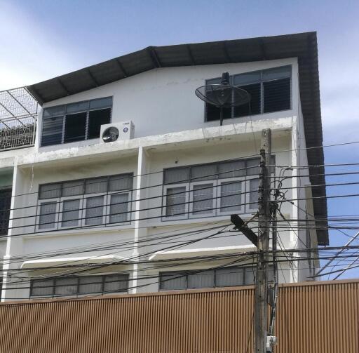 Exterior view of a multi-story residential building with windows and satellite dish