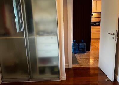 Bedroom with glass-door wardrobe and view into kitchen