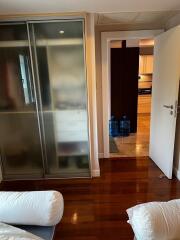 Bedroom with glass-door wardrobe and view into kitchen