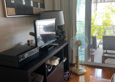 Living room with TV stand, table fan, and balcony access