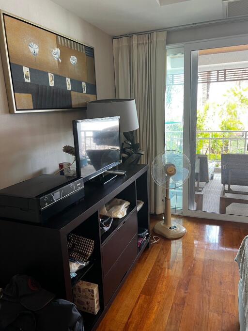 Living room with TV stand, table fan, and balcony access