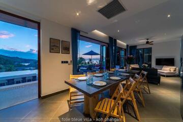 Modern open-plan dining and living area with scenic view, evening light ambiance