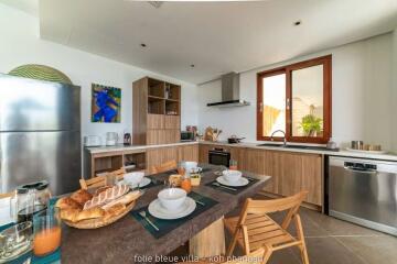 Modern kitchen with wooden cabinets, a stainless steel refrigerator, and various kitchen appliances