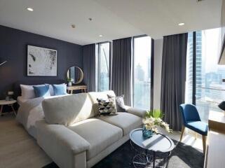 Modern living area with a couch and bedroom in the background with city views